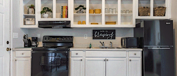 a kitchen with white cabinets and black appliances