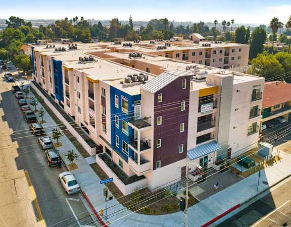 an aerial view of an apartment complex with cars parked on the side of the road