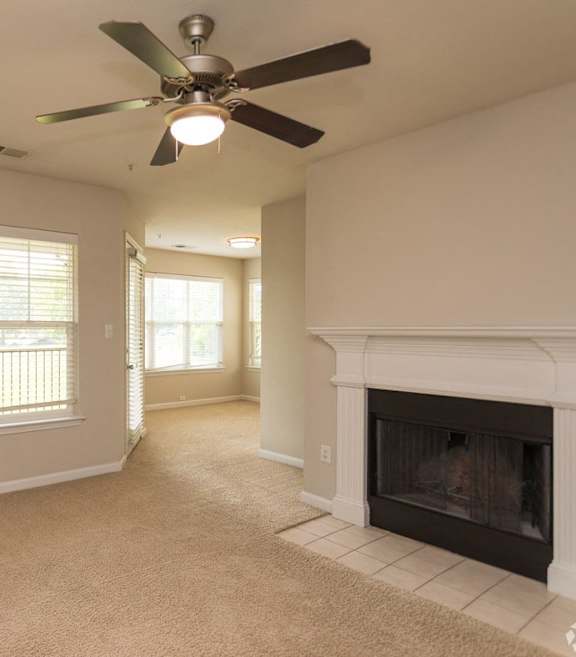 A living room with a fireplace and a ceiling fan.