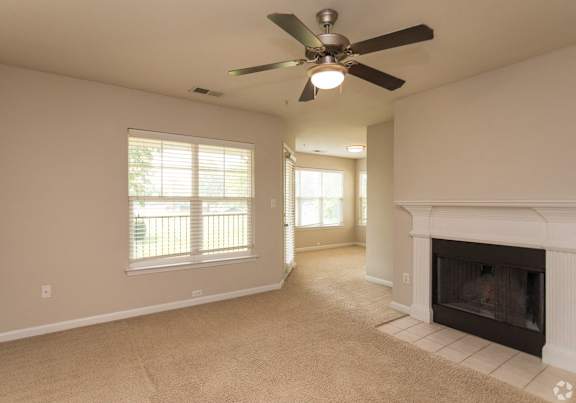 A living room with a fireplace and a ceiling fan.