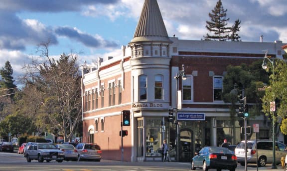 a building with a cone shaped steeple on a city street