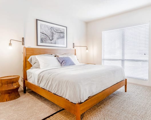 A bedroom with a bed, chair, and picture on the wall.
