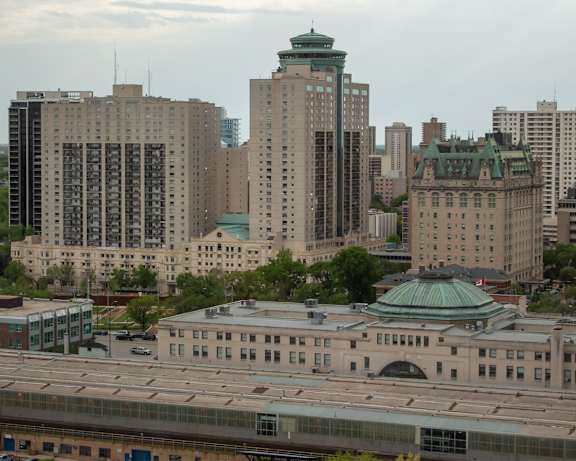 A cityscape with a large building in the foreground and several other buildings in the background.