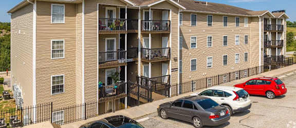 a large tan apartment building with balconies and cars parked in front of it