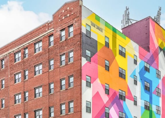 A building with a mural of a colorful house on its side.