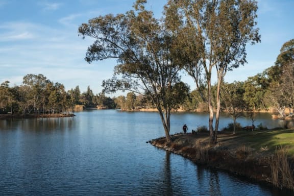 a man sitting on a bench next to a lake