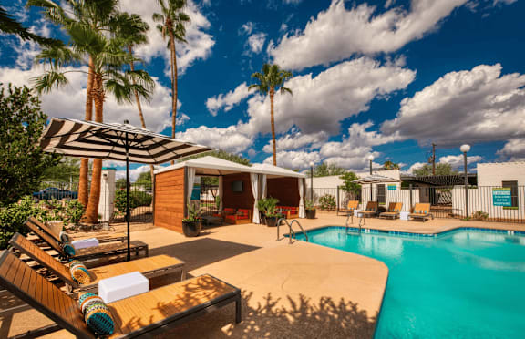 A pool area with a sun lounger and a striped umbrella.