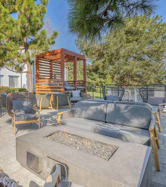 A patio with a fire pit and chairs.