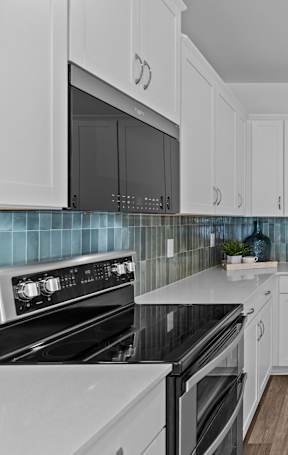 A kitchen with white cabinets and a black stove top oven.