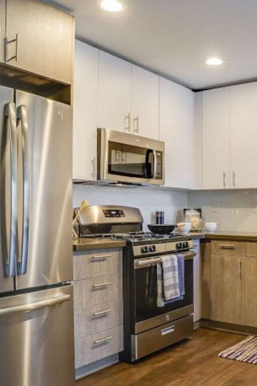 A modern kitchen with a stainless steel refrigerator and wooden cabinets.at Solterra At Civic Center, Norwalk, CA