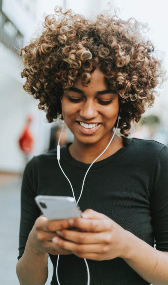 a woman looking at her cell phone while wearing headphones