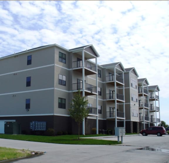 an apartment building with a red car parked in front of it