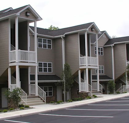 Apartment complex with a parking lot in front.