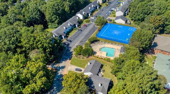 An aerial view of a neighborhood with a blue pool and tennis court.