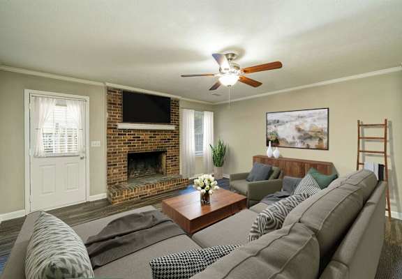 A living room with a grey couch and a fireplace.