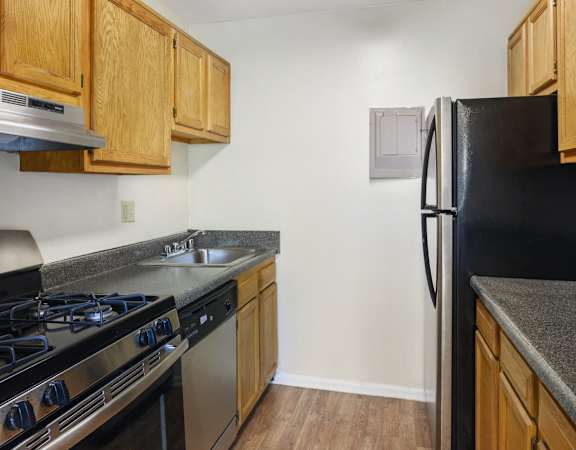 A kitchen with wooden cabinets and a black refrigerator.