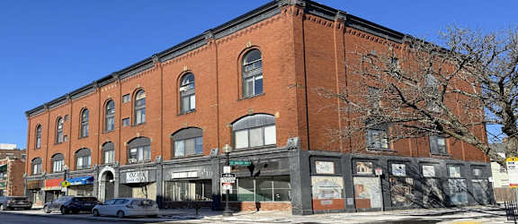 A red brick building with a black awning on the corner.