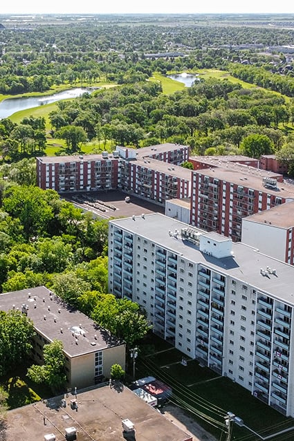 an aerial view of a large apartment complex with trees and a river in the background