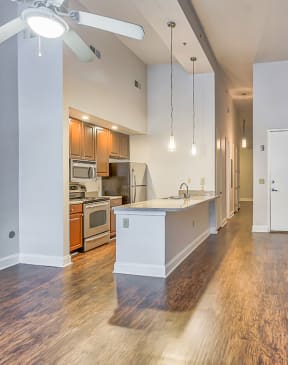 a kitchen and living room with a brick wall and hardwood floors