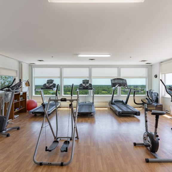 a gym with cardio equipment and a large window with a view of the ocean