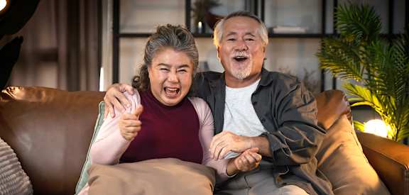an older couple sitting on a couch with their arms around each other