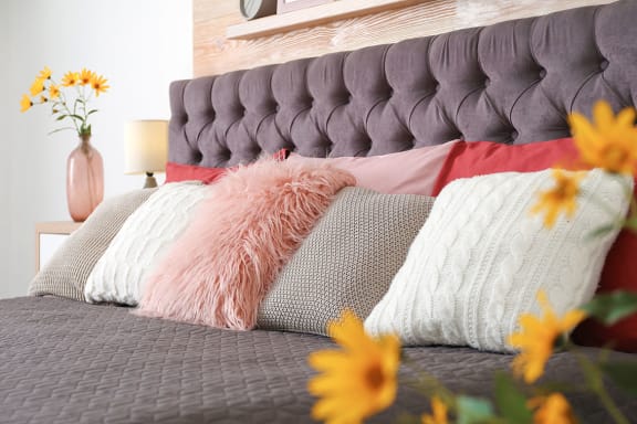 a bed with pillows and a vase of flowers