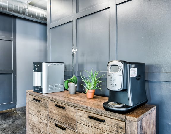 a coffee machine and a toaster sit on a wooden dresser in a gray room