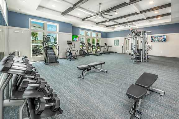 A spacious gym with a variety of equipment including treadmills, elliptical machines, and dumbbells.