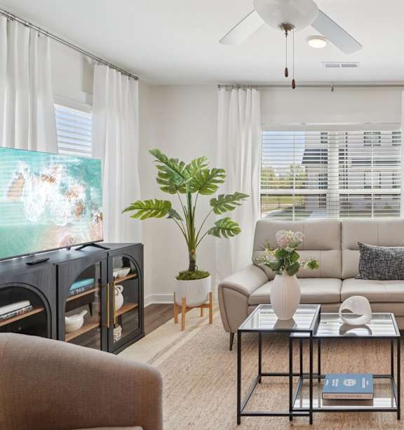 A living room with a large couch, a coffee table, and a ceiling fan.