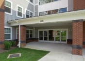 Thumbnail 4 of 6 - the entrance to an apartment building with a walkway and grass