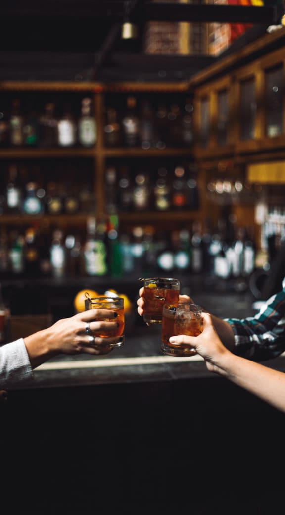 two people holding their drinks at a bar