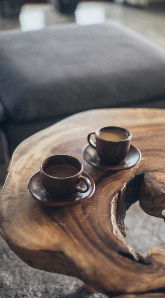 two cups of coffee on a wooden table in a living room