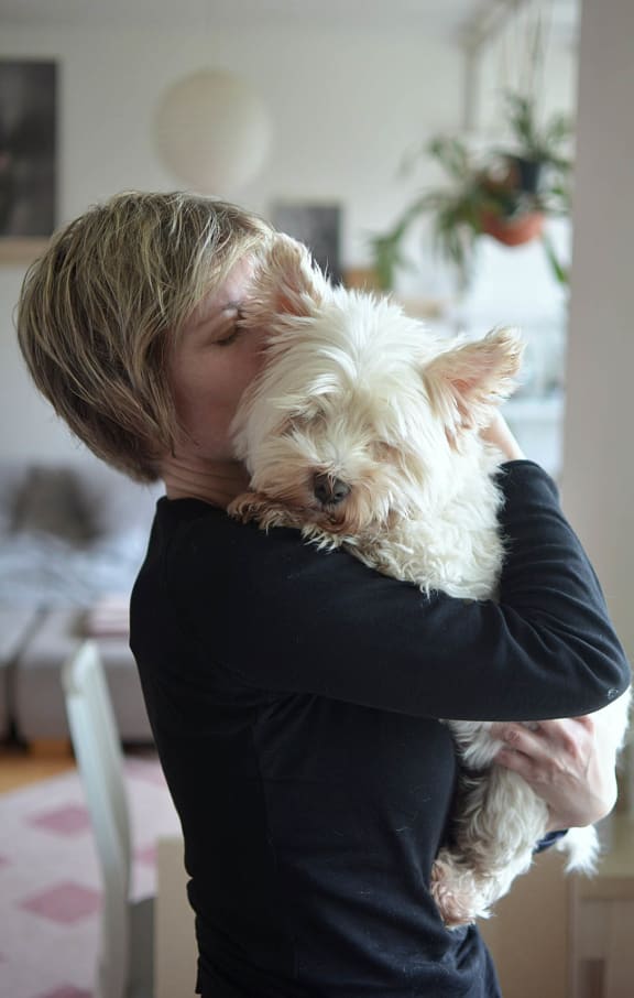 a woman holding a white dog in her arms