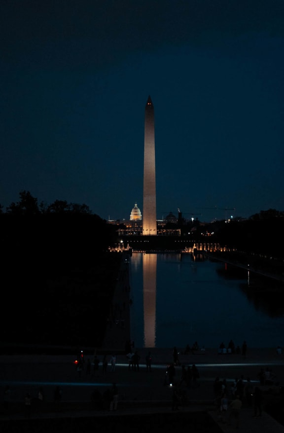 the monument at night with the reflecting pool and the capitol building