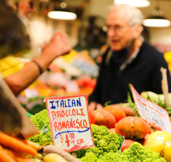 a man standing behind a display of vegetables in a market