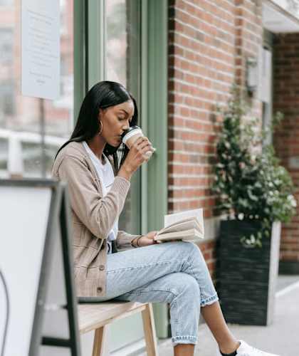 a woman sitting on a bench drinking coffee and reading a book at 2000 Oasis  Apartments, Atlanta, GA