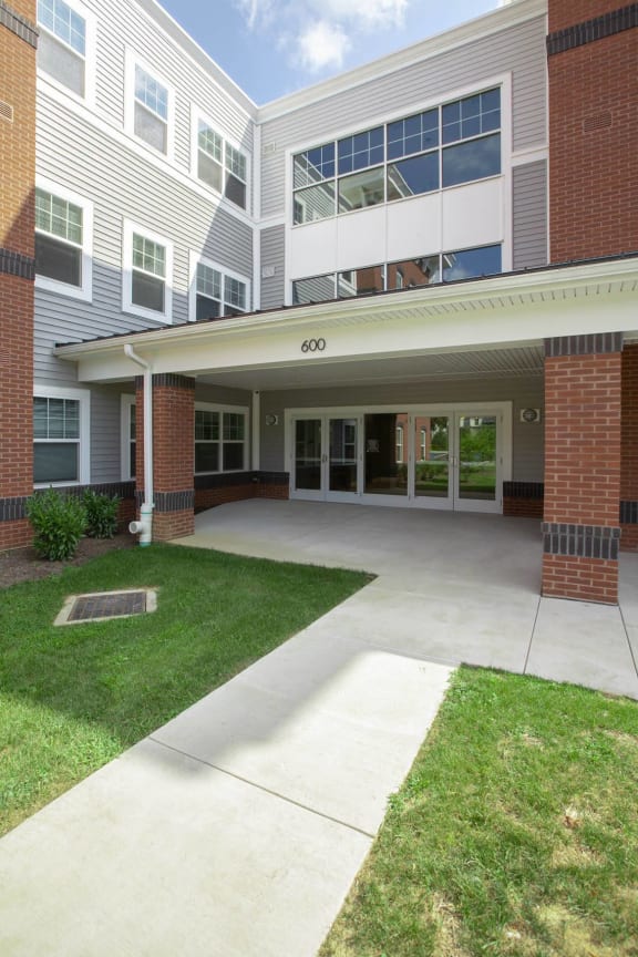 the entrance to an apartment building with a walkway and grass