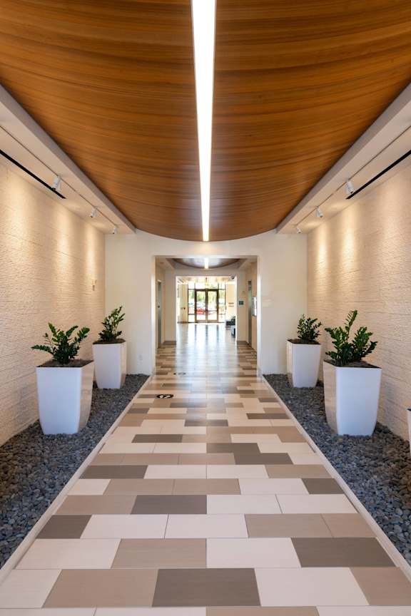 A long hallway with a tiled floor and white planters on either side.