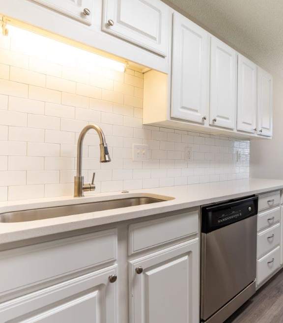 A kitchen with white cabinets and a stainless steel dishwasher.