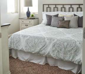 A bedroom with a bed, dresser, and ceiling fan at Meadowlark Place Apartments, IA, 50111