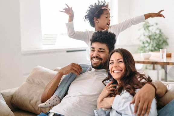 a man and woman sitting on a couch with their daughter