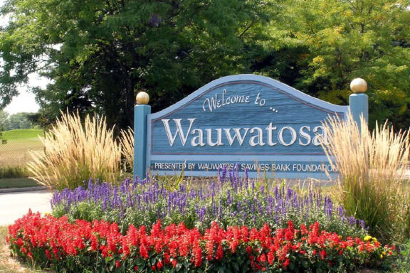 a blue sign with white lettering in the middle of a flower garden