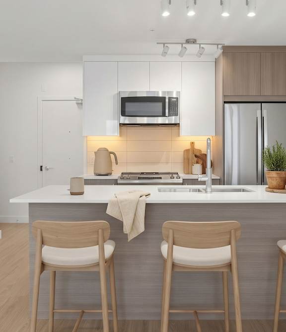 A modern kitchen with a white countertop and wooden chairs.