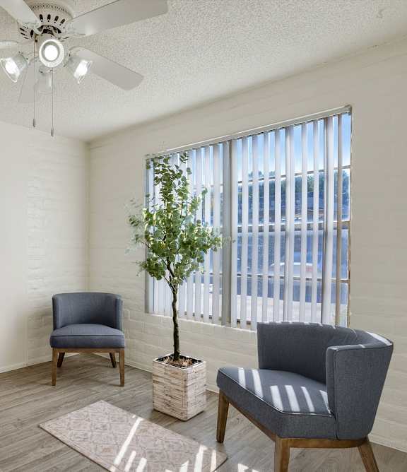A room with a ceiling fan and two chairs.