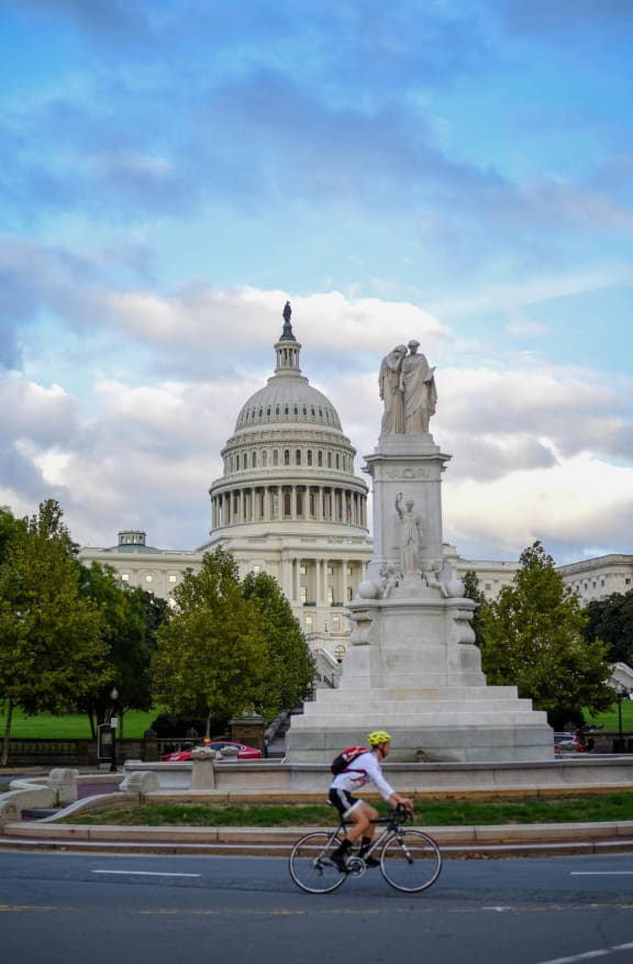 a man riding a bike past the capitol building