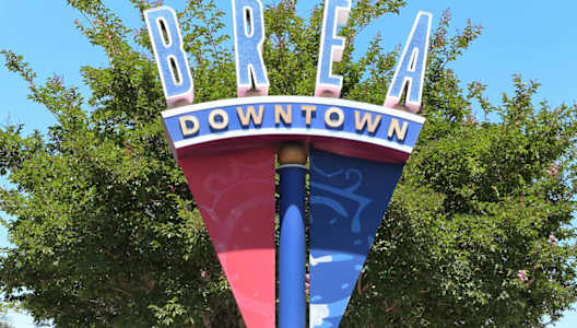 A street sign for Brea Downtown stands on a pole.