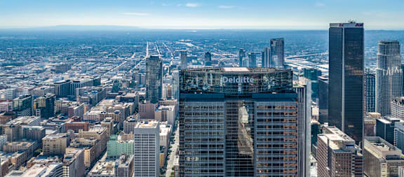 A cityscape with a large building in the foreground and a clear sky above.