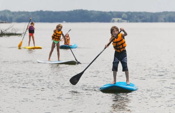 a group of children riding paddle boards at The Residence at Marina Bay in Irmo, SC 29063