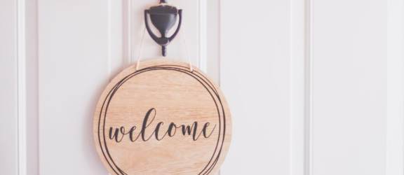 a wooden hoop with the word welcome on it and a christmas wreath hanging on a