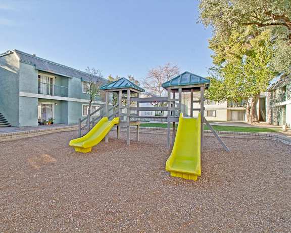 A playground with a yellow slide in front of apartment buildings. at Missouri Crossing, Phoenix, Arizona